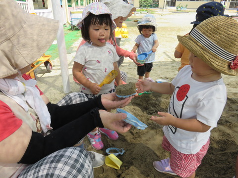 １歳児保育士と一緒に砂場あそび