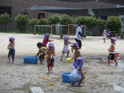 保育士や友達と水鉄砲で水を掛け合っている様子（年少組）